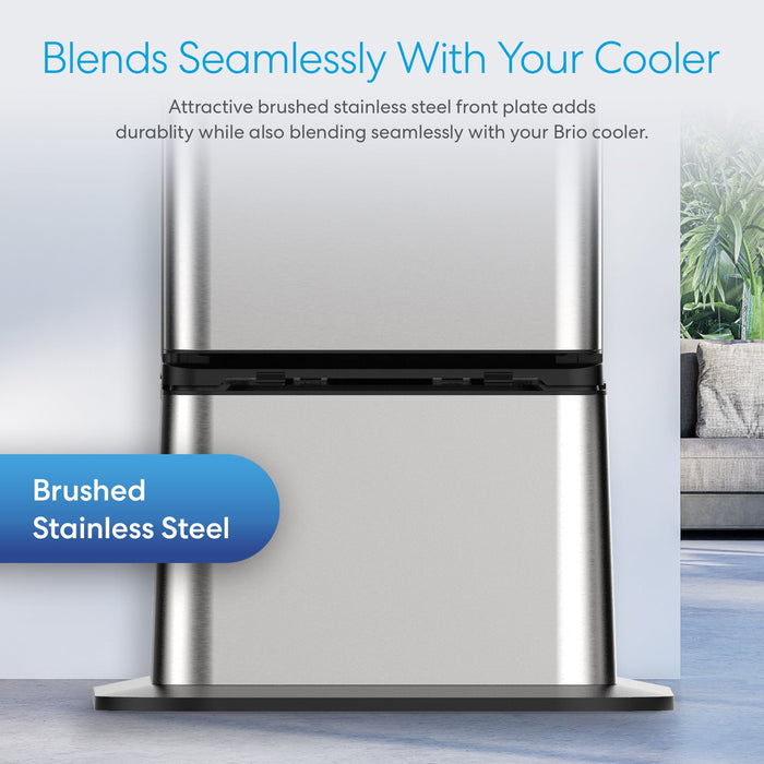 Close-up of the Brio Water Cooler Base – 720 Series Ice Maker Bottled & Bottleless, showcasing its seamless brushed stainless steel design and durability. A modern living room with a plant and gray sofa appears in the background.
