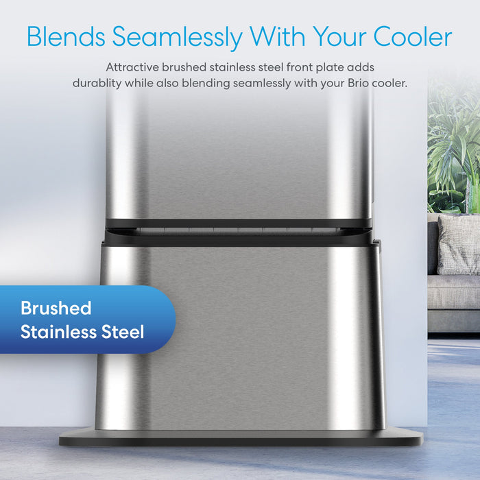 Close-up of the Brio Water Cooler Base, designed for Brio 430 Series Bottled & Bottleless Water Coolers, showing brushed stainless steel durability and seamless fit in a modern living room with couch and plant in background.