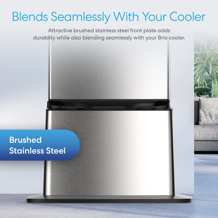 Close-up of the brushed stainless steel front plate on the Brio Water Cooler Base – 530 Series Bottled & Bottleless Water Cooler, showcasing its seamless design and durability. A couch and plant appear blurred in the background.