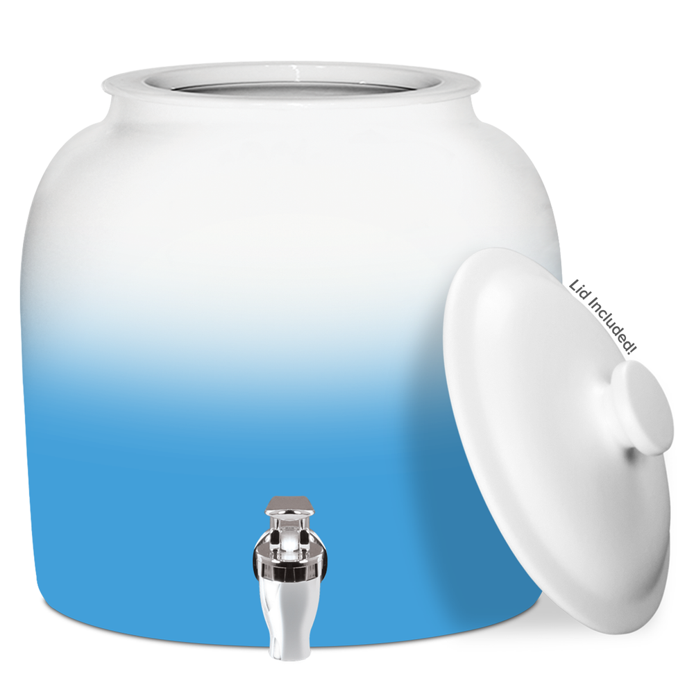 The GEO Porcelain Ceramic Crock Water Dispenser – Gradient Colors features a light blue and white gradient finish, a silver spigot, and a matching white lid propped to the side. This BPA-free container is perfect for dispensing water with style.