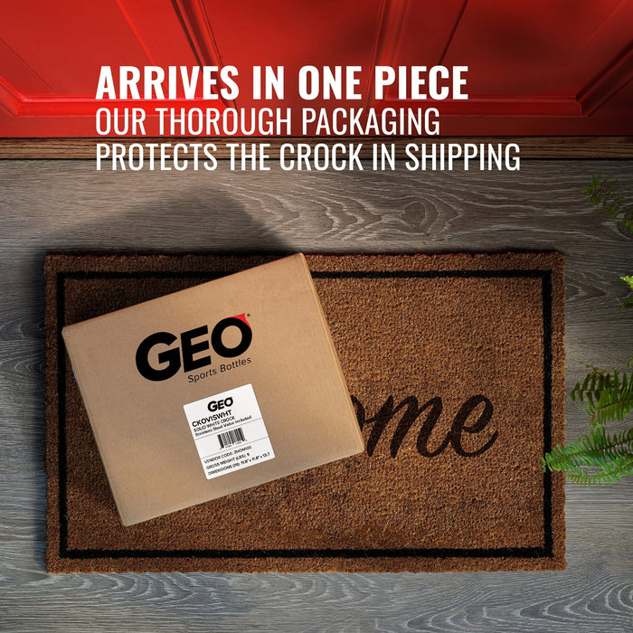 A box labeled GEO Porcelain Ceramic Crock Water Dispenser – Black w/ Yellow Speckles sits on a welcome doormat by a red door. Text above: Arrives in one piece. Our secure packaging protects your BPA-free ceramic water dispenser.