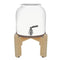 The GEO Porcelain Ceramic Crock Water Dispenser in white features a BPA-free ceramic body, a metal spigot, and sits securely on a four-legged wooden stand.
