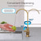 A hand washes a green apple under the Brio Curvy Classic Series Water Faucet – Brushed Gold, featuring a 360° rotating spout, splash-free directed stream, and user-friendly design as water flows smoothly into the sink.