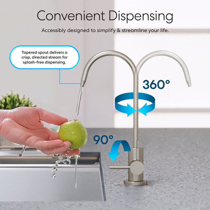 A hand rinses a green apple under the Brio Modern Series Water Faucet – Brushed Nickel, which features 360° rotation, 90° handle movement, dual spouts, and splash-free water dispensing.