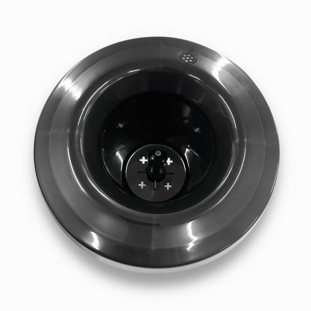 A top-down view of a shiny stainless steel Non-Spill Top 420, 520 Coolers base with a dark central blade and visible plus and minus symbols, set against a white background.