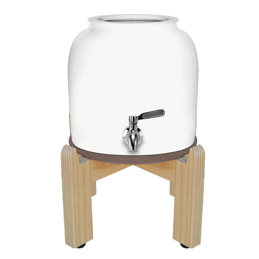 The GEO Porcelain Ceramic Crock Water Dispenser in white features a BPA-free ceramic body, a metal spigot, and sits securely on a four-legged wooden stand.